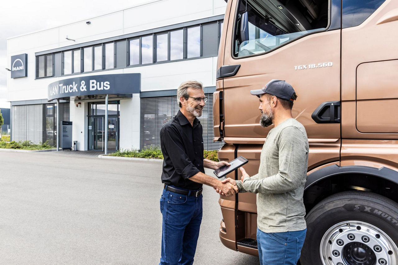 Zwei Männer geben sich vor einem MAN-Lkw bei MAN Truck & Bus die Hand